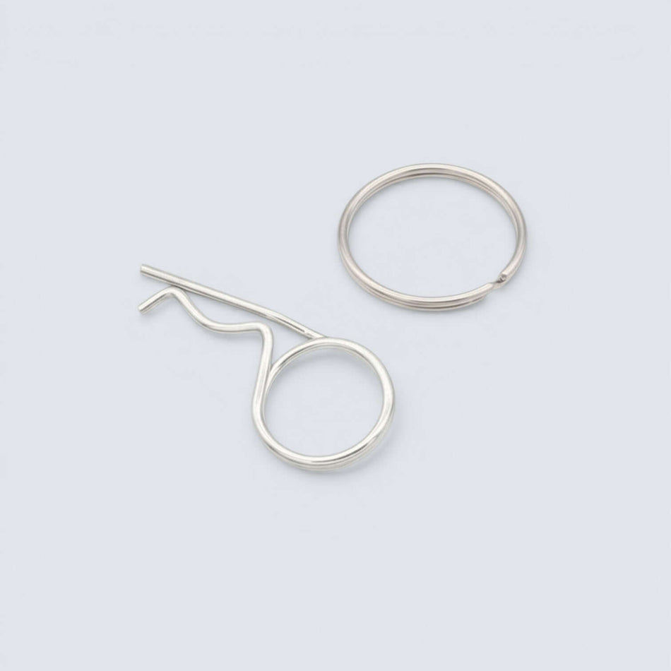 Bild på en fjädersprint och en låsring i rostfritt stål mot grå bakgrund